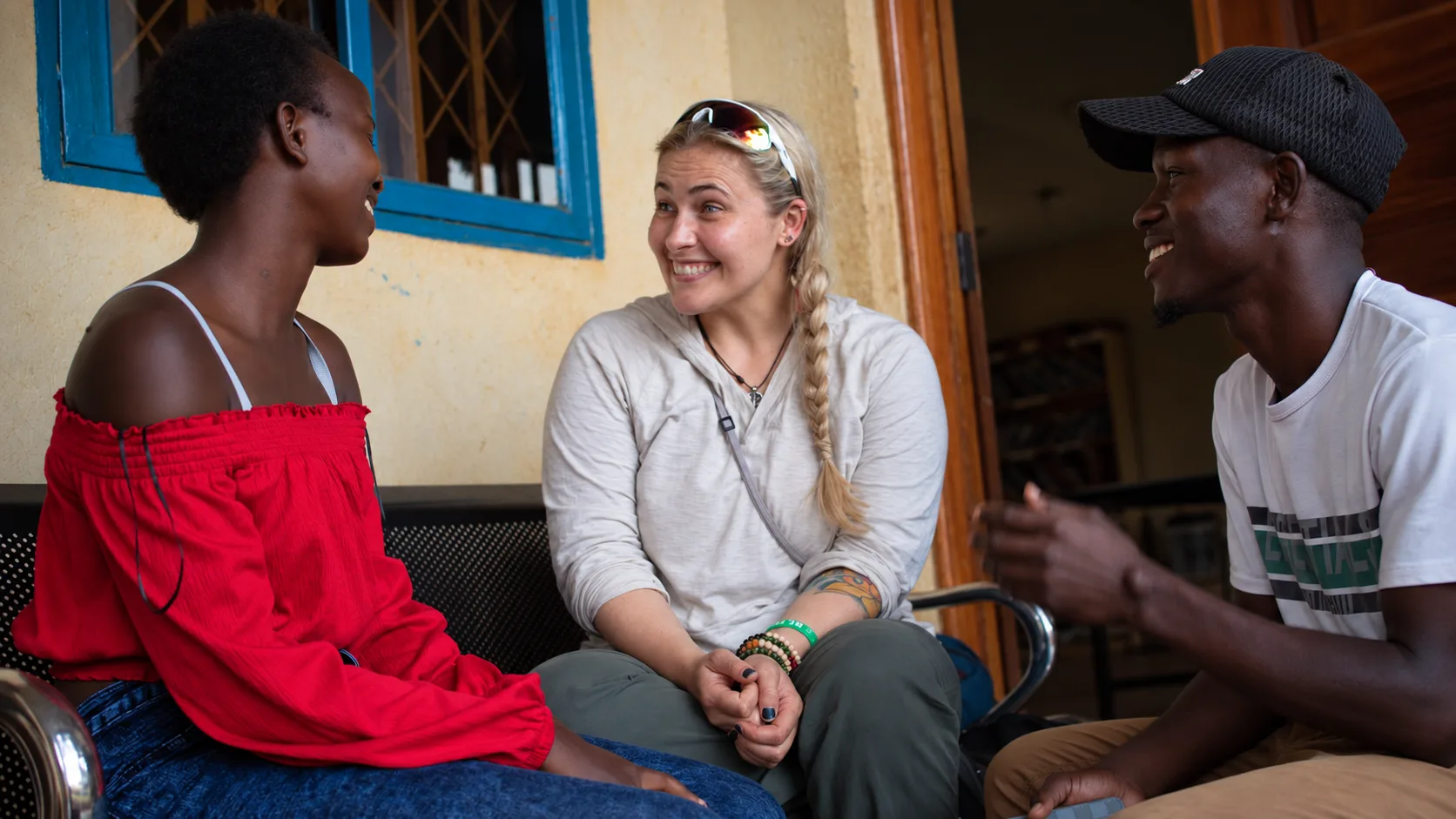 Janelle in conversation with two storytellers seated outside a building in Uganda